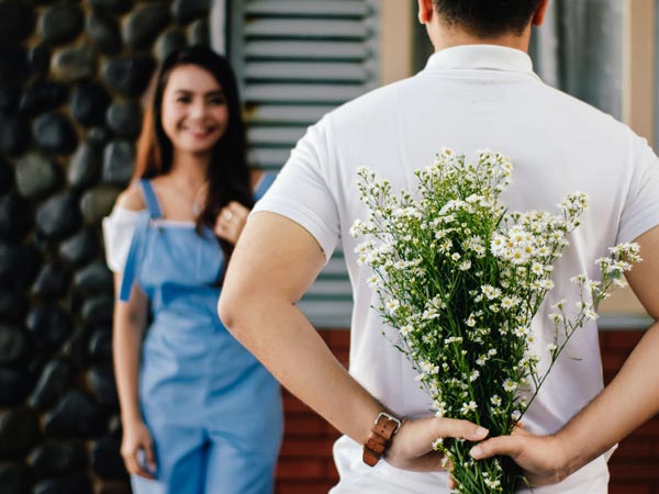 A man trying to hide a boquet of flowers from a Ukrainian girl.