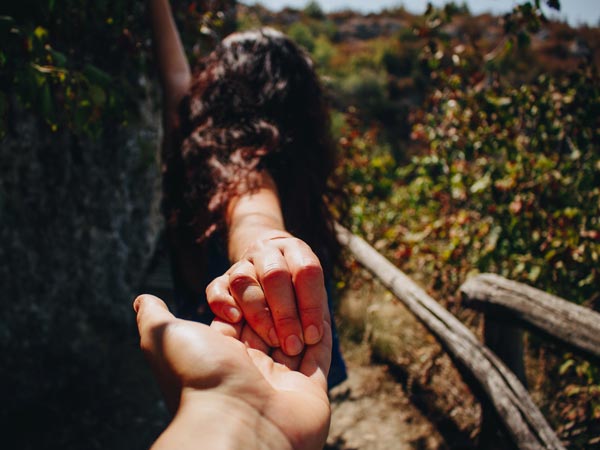 Woman extending her hand to the back reaching out to another person.