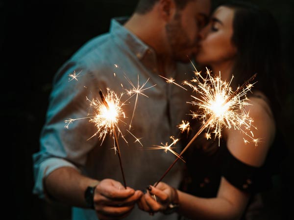 man and woman kissing while holding sparklers