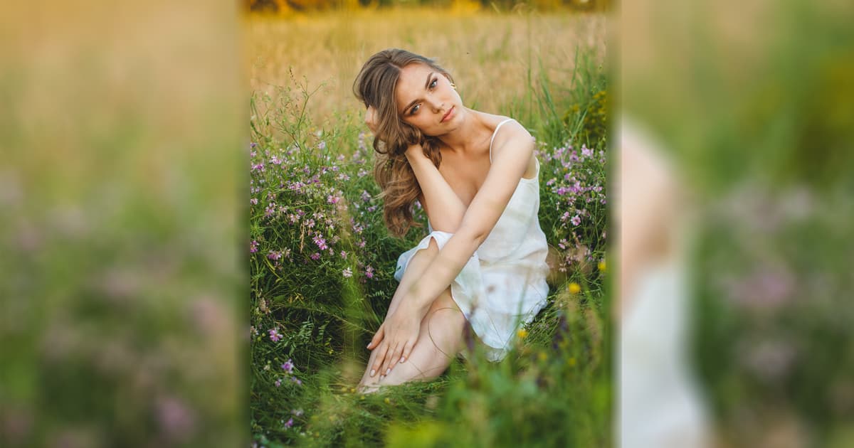 A photo of a woman in a white dress sitting on gras